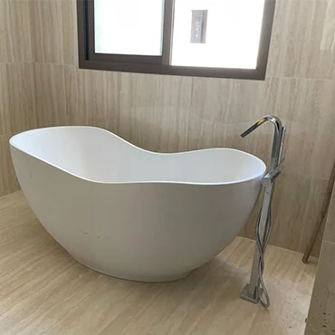 Freestanding white bathtub against warm stone-look wall finishes
